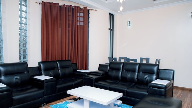 Una sala de estar moderna con sofás de cuero negro, una mesa de centro blanca y una alfombra azul estampada.