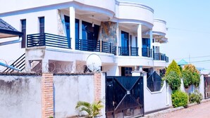 A modern two-story house with a balcony, a satellite dish, and a gated entrance.