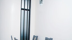 A dining area with a rectangular table and six chairs, a window with vertical blinds, and a light switch on the wall.