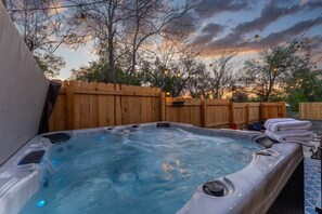 A hot tub with a wooden deck and a wooden fence in the background.