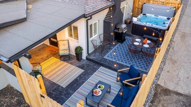 A backyard patio with a hot tub, outdoor seating, and a grill area. - The Copper Cottage: An Eclectic Oasis with Hot Tub (Berkley)