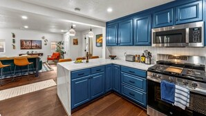 A modern kitchen with blue cabinets, stainless steel appliances, and a central island. - The Copper Cottage: An Eclectic Oasis with Hot Tub (Berkley)