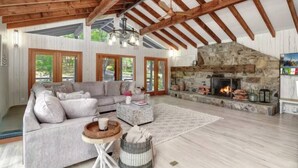 Un salón amplio con chimenea de piedra, vigas de madera y un sofá grande.