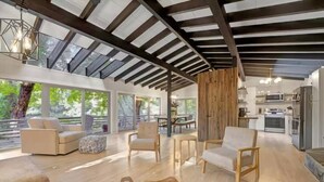 Amplia sala de estar con techo alto, vigas de madera y grandes ventanales con vistas al exterior.