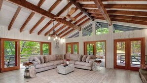 Amplia sala de estar con un sofá seccional grande, vigas de madera, ventanas amplias y vistas al exterior.