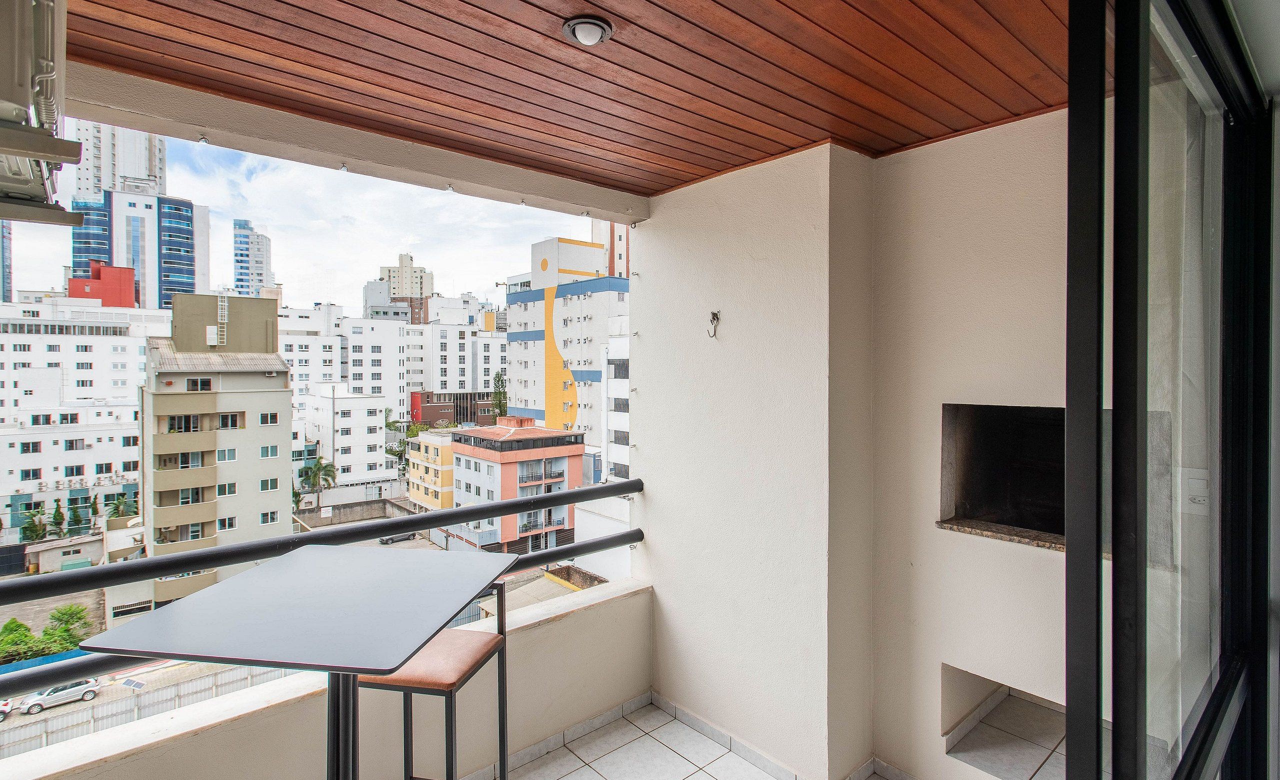 A balcony with a table and chairs, a TV, and a city view.