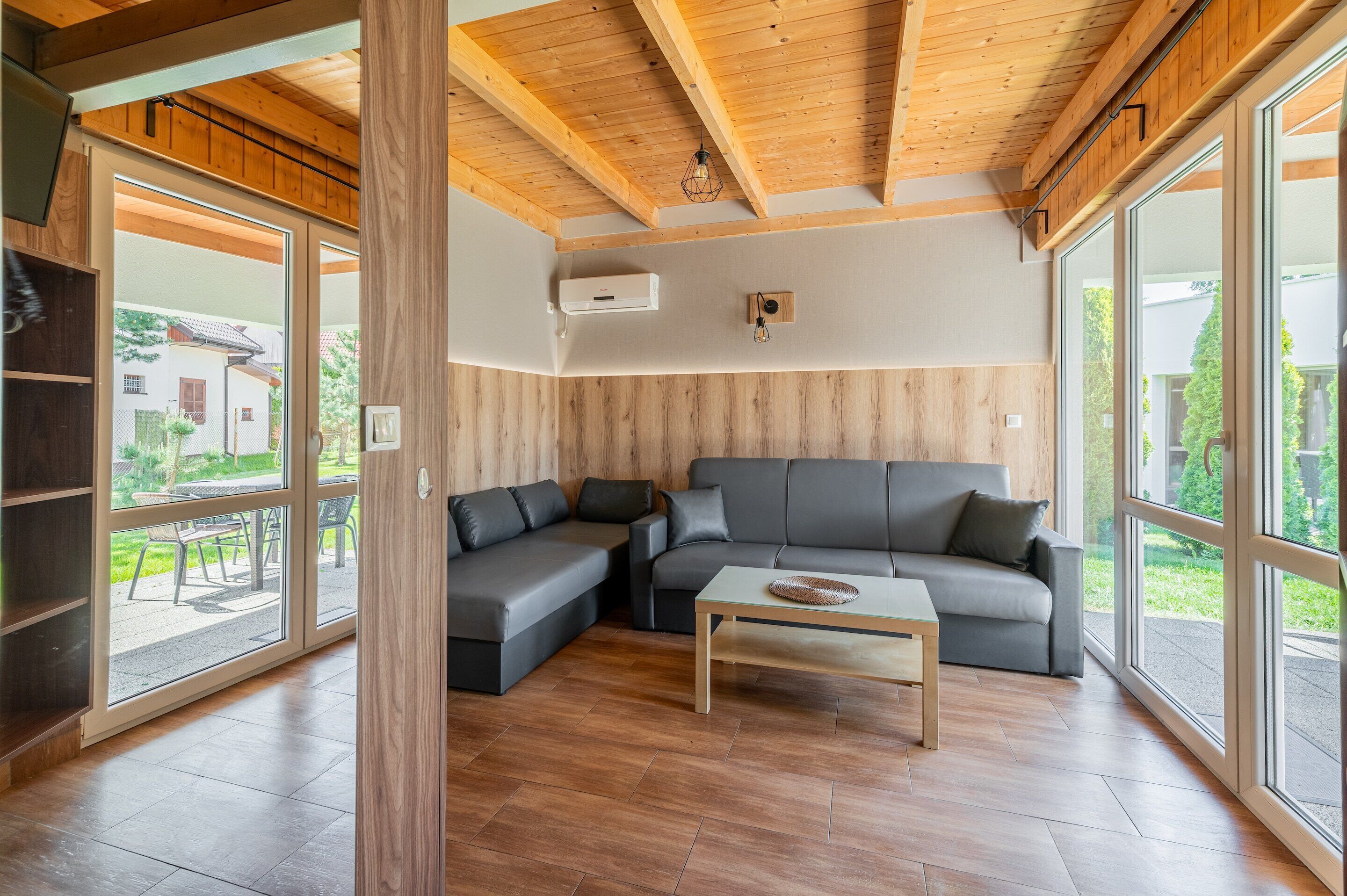 Een moderne woonkamer met een modulaire bank, een salontafel en grote ramen met uitzicht op de omgeving.