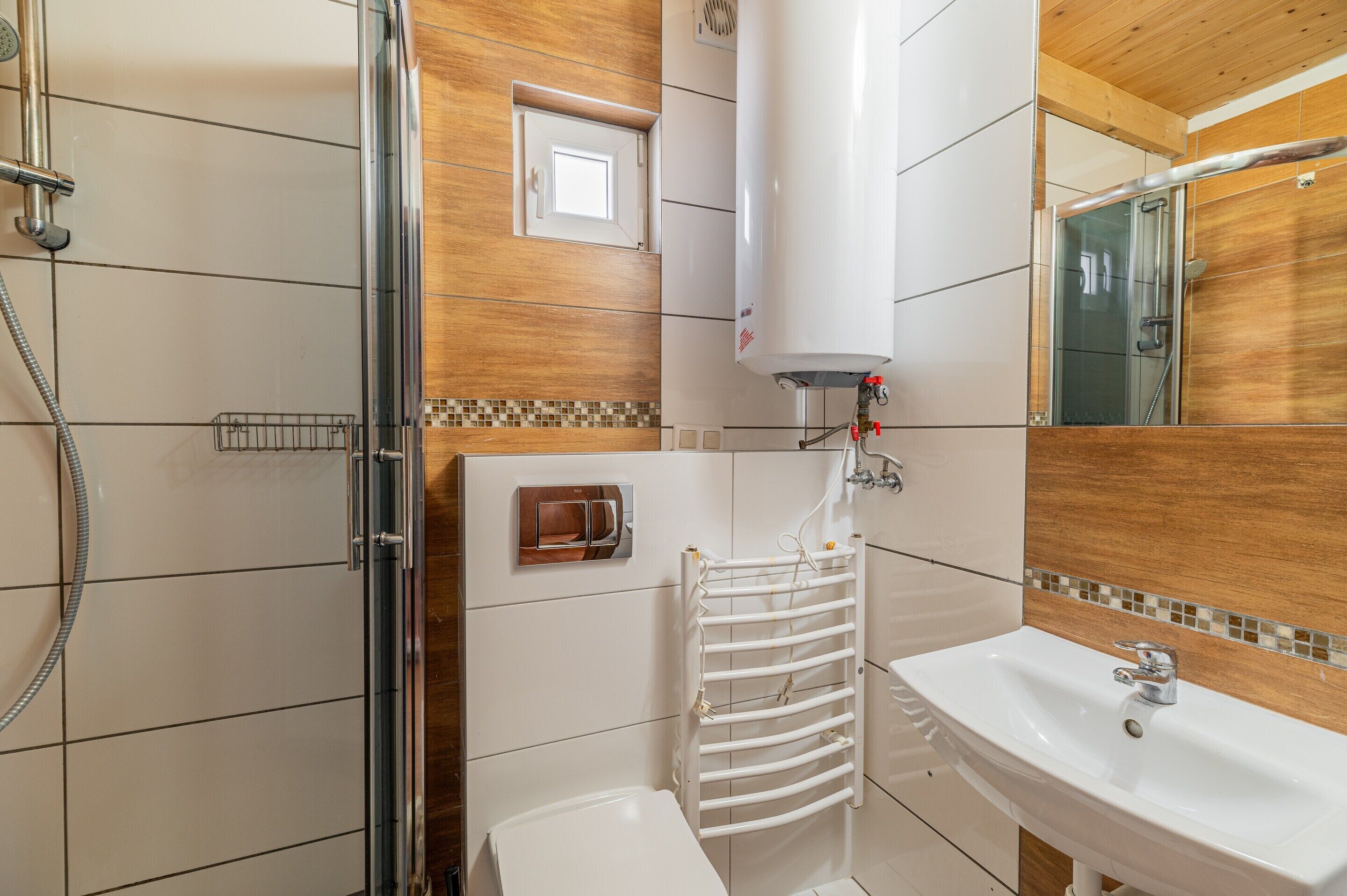 A modern bathroom with a glass shower enclosure, a white sink, and a towel rack.