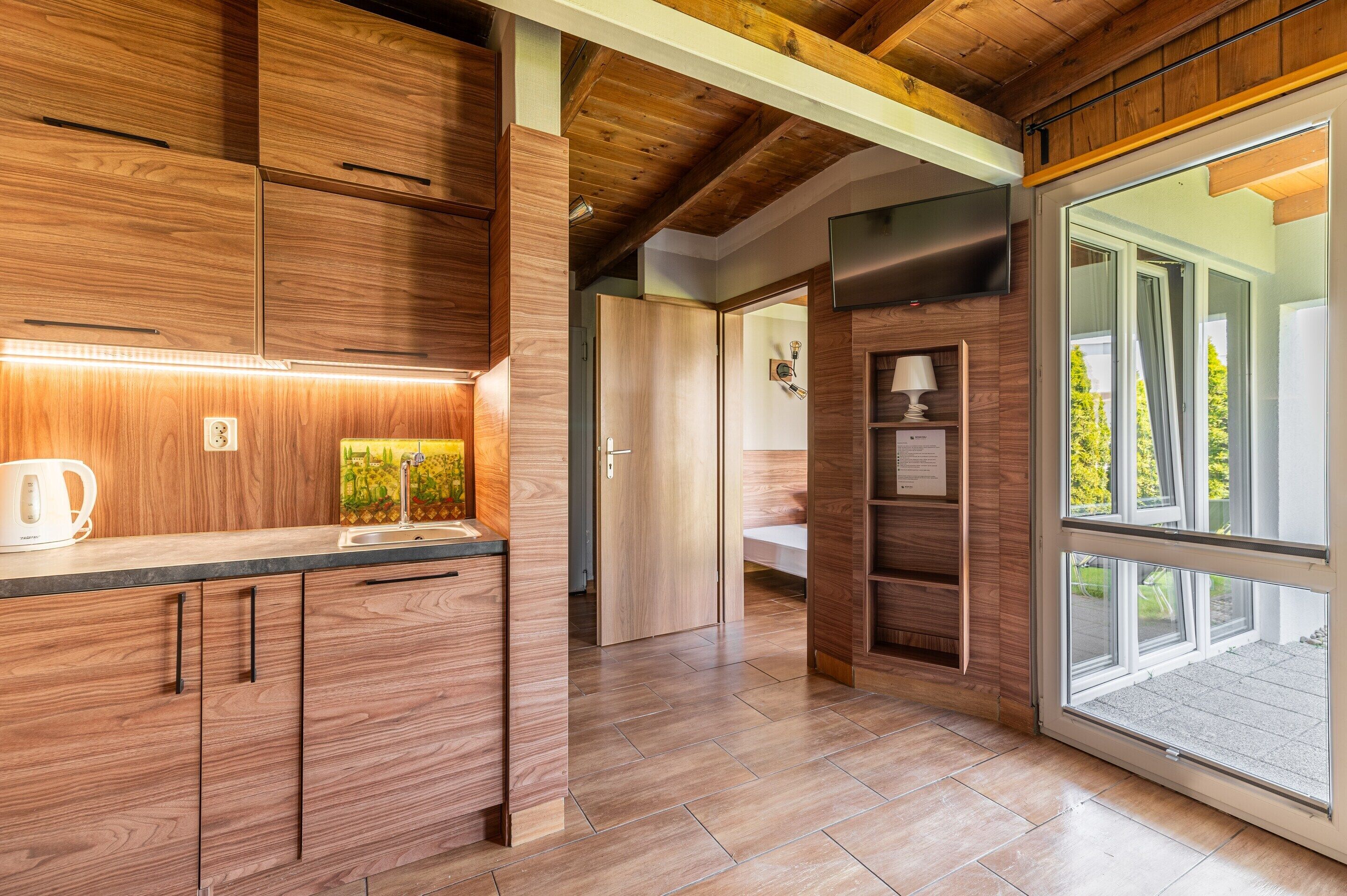 A modern kitchen with wooden cabinets, a built-in oven, and a large window.