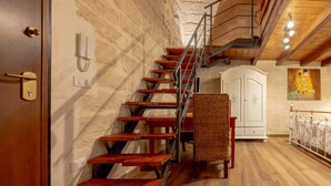 A wooden staircase with metal railings, a wicker chair, a white cabinet, and a painting on the wall. - La Dimora di Marco – Exclusive Art Rooms in Salento (Melendugno)
