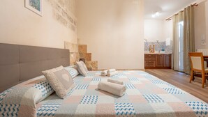 Ein Schlafzimmer mit Bett, Kissen, Bettdecke, Kopfteil, einem Badezimmer mit Waschbecken und einem Sessel.