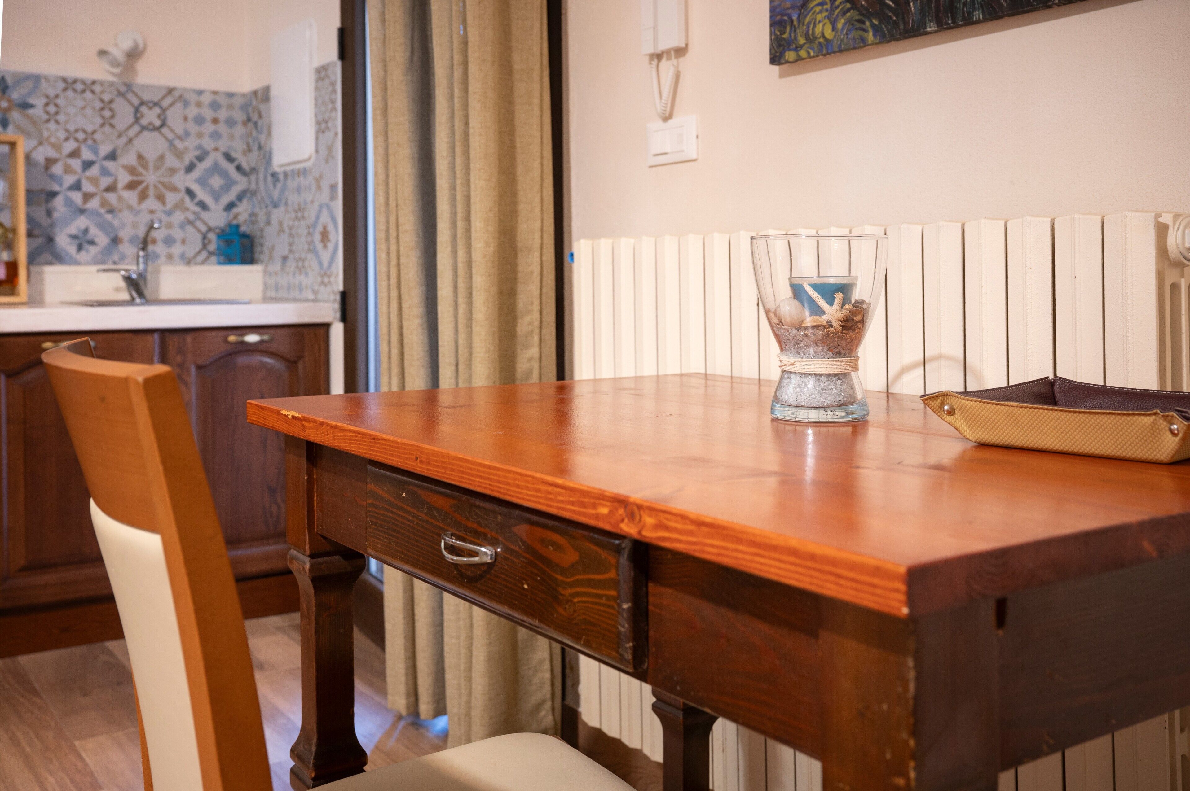 A wooden dining table with a glass vase and a woven basket.