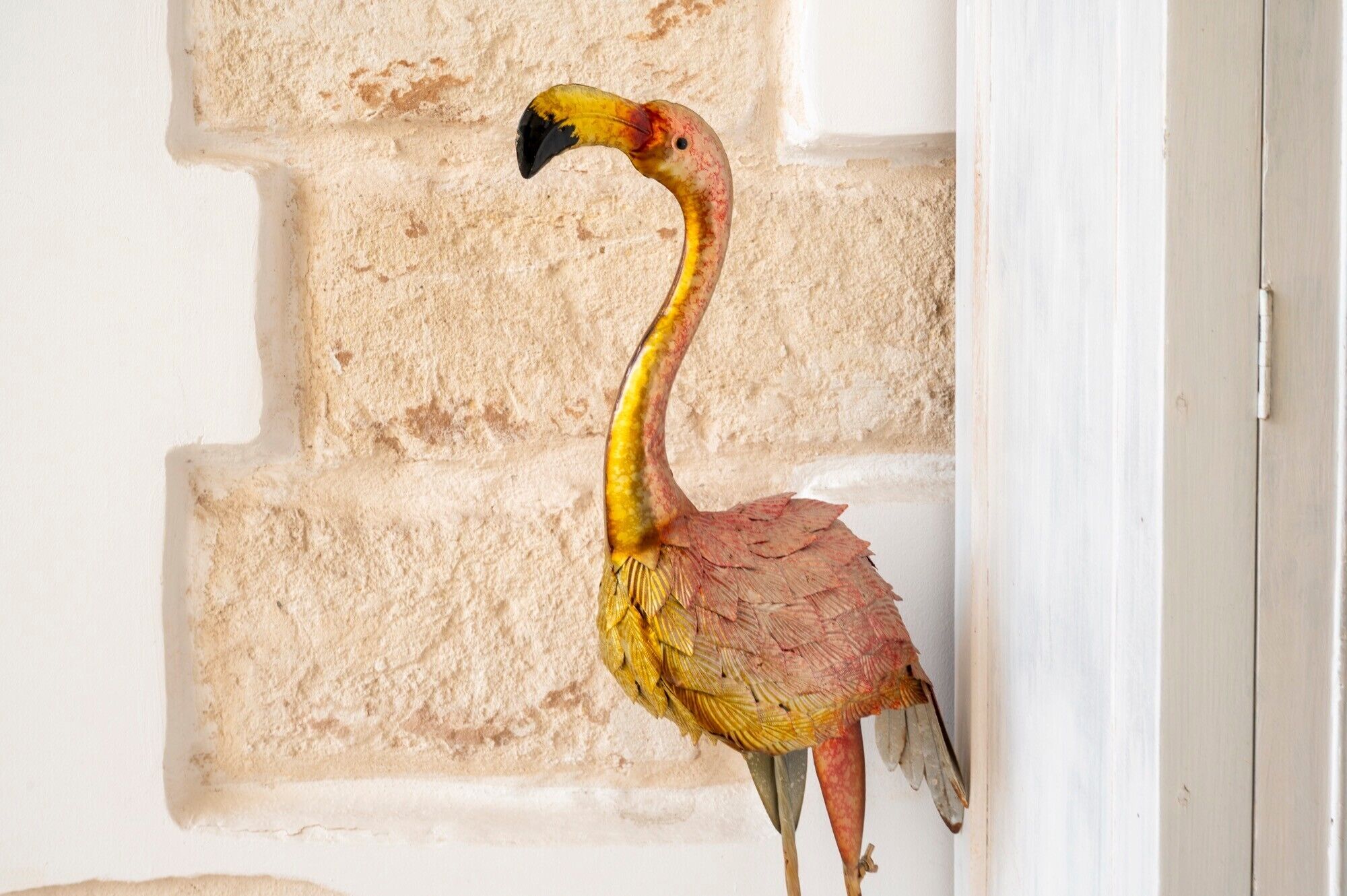 Un flamant rose se tient devant un mur à texture.