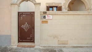 A brown door with a decorative emblem, a mailbox, a small window, and a plaque on a beige wall.