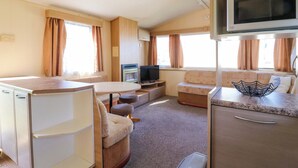 A compact RV interior with a kitchenette, a small TV, and a seating area. - Singh Leite &amp; Luisa Family Caravan (Clacton-on-Sea)