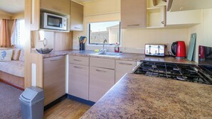 A compact kitchen with a microwave, stove, sink, and cabinets. - Singh Leite &amp; Luisa Family Caravan (Clacton-on-Sea)