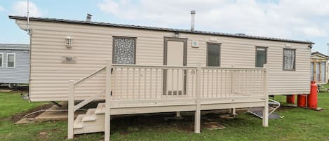 A mobile home with a front porch, a chimney, and a small deck.