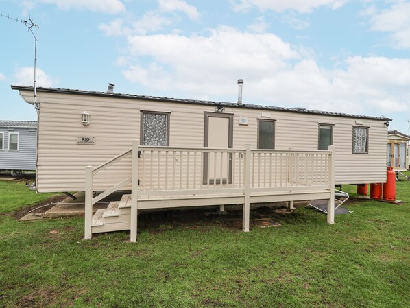 A mobile home with a front porch, a chimney, and a small deck. - Singh Leite & Luisa Family Caravan (Clacton-on-Sea)
