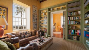 Een gezellige woonkamer met een leren bank, een bijzettafeltje en een boekenplank vol boeken en decoratieve objecten.