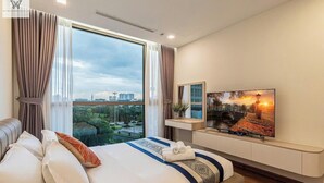 A modern hotel room with a large bed, a TV, and a city view. - The Landmark Residence Of Central City (Ho Chi Minh City)