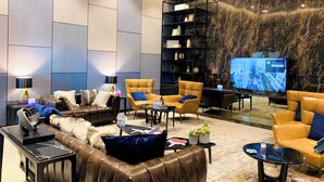A modern lounge area with leather sofas, armchairs, and a TV screen. - The Landmark Residence Of Central City (Ho Chi Minh City)