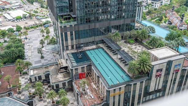 A high-rise building with a rooftop pool, surrounding greenery, and a busy street below. - The Landmark Residence Of Central City (Ho Chi Minh City)