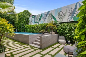 En modern uteplats med en pool, trappsteg av sten och en väggmålning med blommotiv.