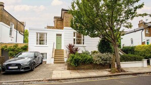 Une maison moderne à deux étages, avec une voiture garée dans l’allée.