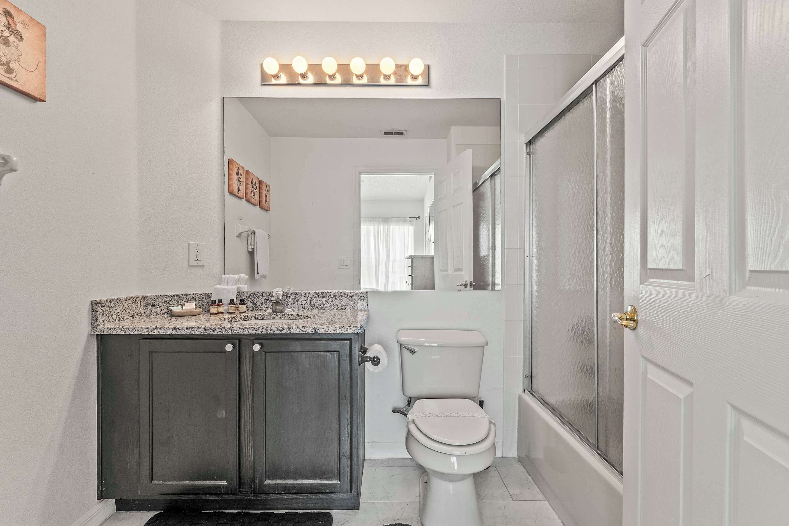 Une salle de bain avec un meuble-lavabo foncé, des toilettes et un espace douche.