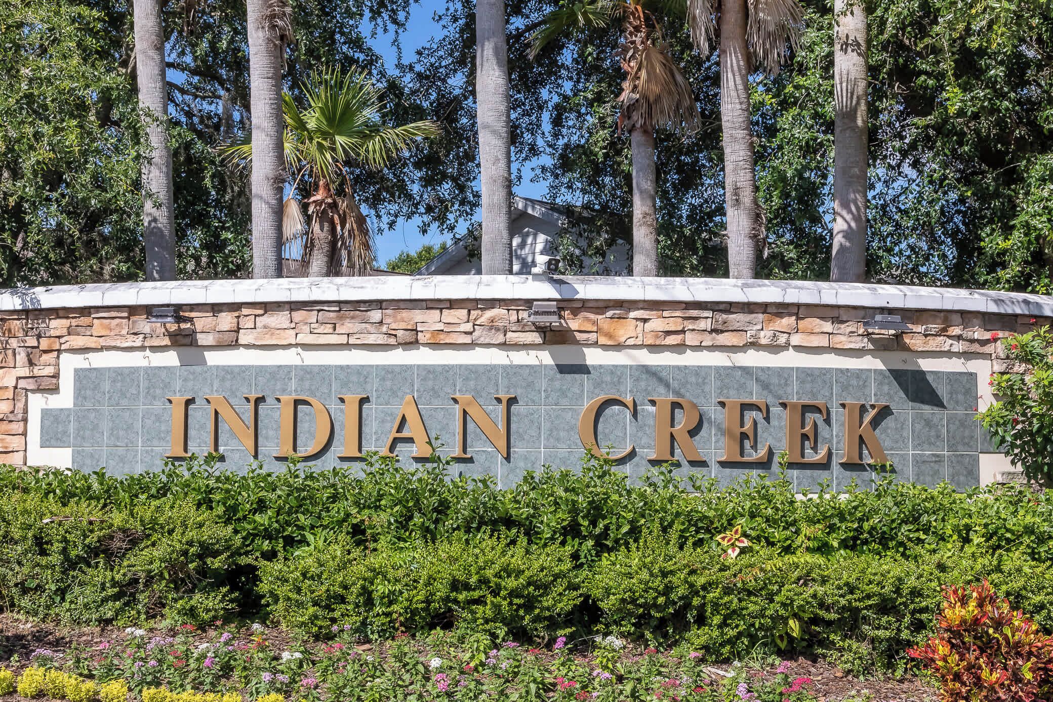 Ein Schild mit der Aufschrift 'INDIAN CREEK', umgeben von Grünpflanzen und Palmen.