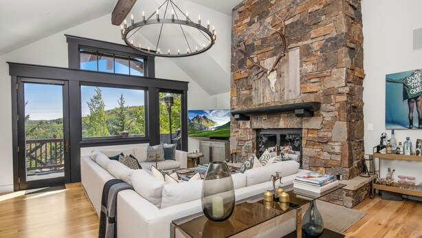 Un salón amplio con un sofá blanco, una mesa de centro de vidrio y una chimenea de piedra.