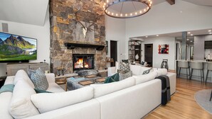 Una sala de estar moderna con chimenea de piedra, un televisor de pantalla plana grande y una zona de estar acogedora.