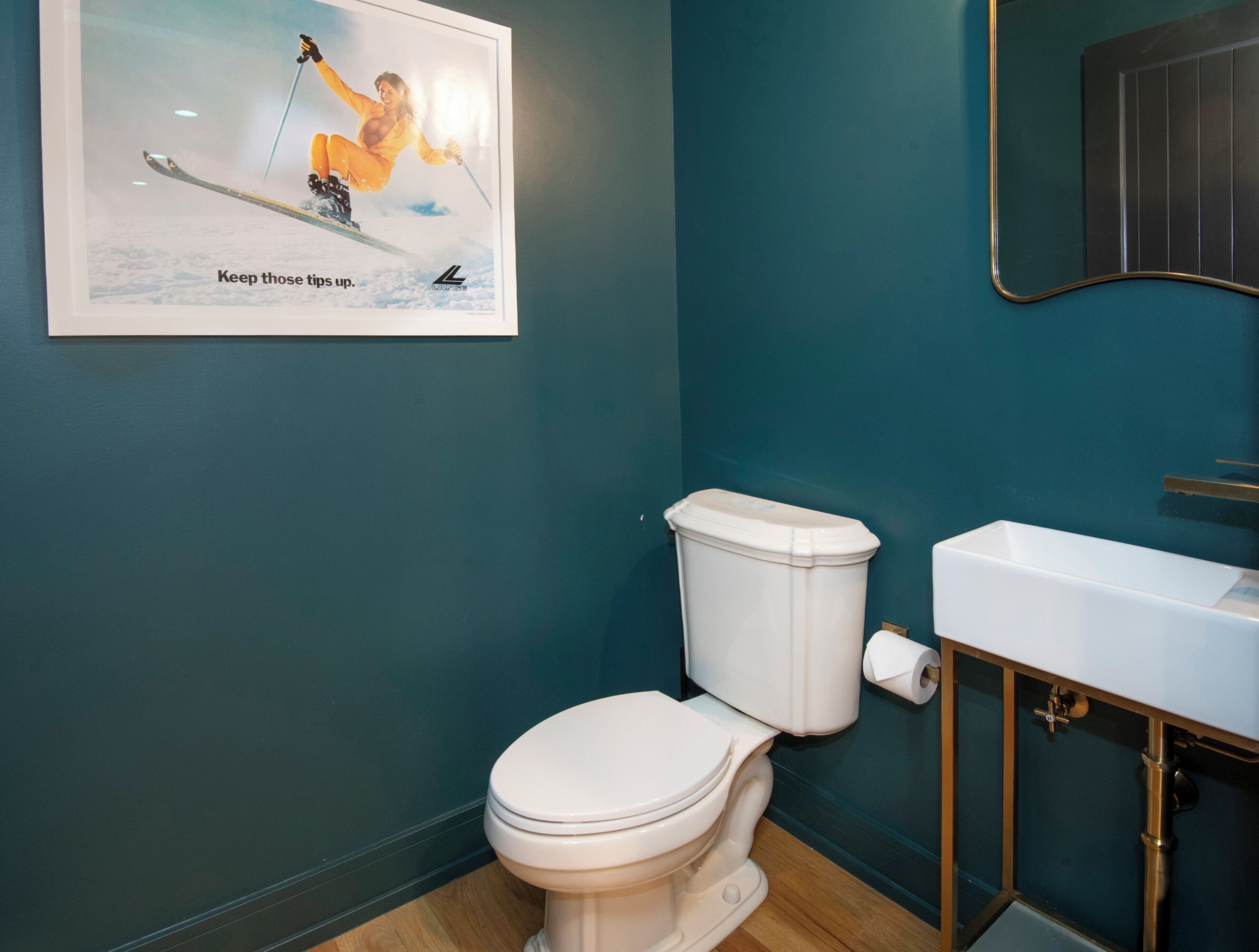 Une salle de bain avec des toilettes blanches, un lavabo et un miroir.