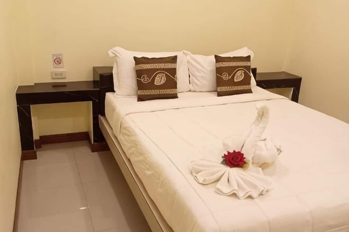A hotel room with a neatly made bed, a nightstand, and a wall-mounted sign.