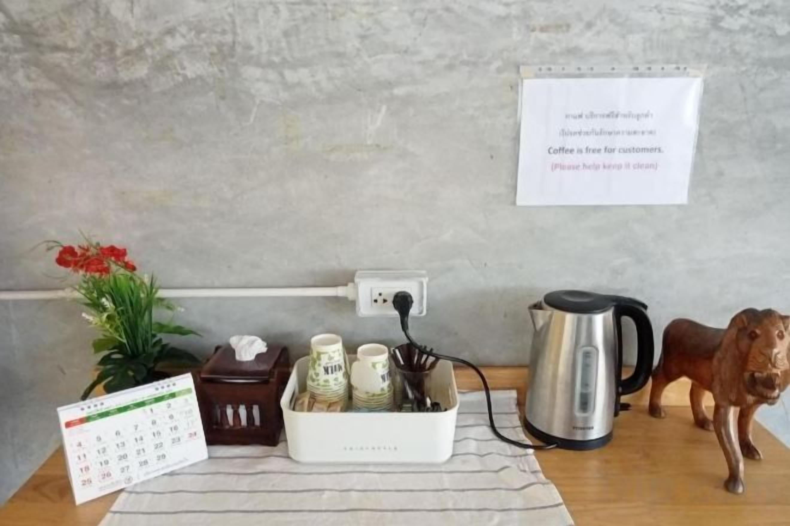 A coffee station with a calendar, a coffee pot, and a sign indicating free coffee for customers.