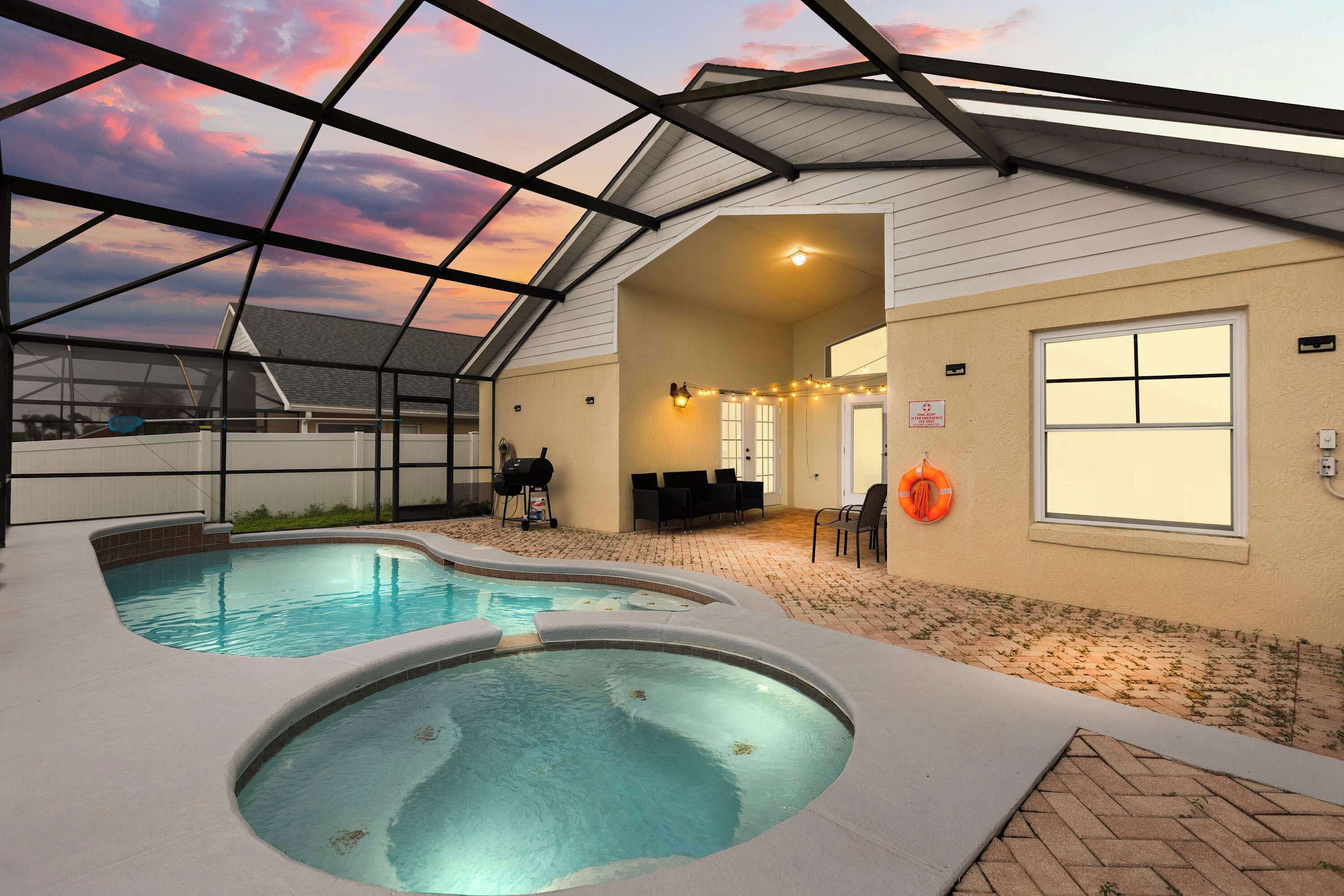 A pool area with a glass ceiling, a hot tub, and a covered seating area.
