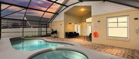 A pool area with a glass ceiling, a hot tub, and a covered seating area.