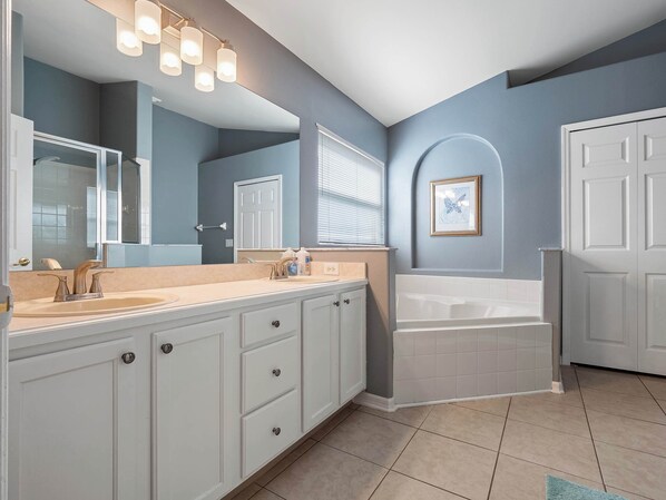 A bathroom with a double sink vanity, a large mirror, a bathtub, and a framed butterfly artwork on the wall.