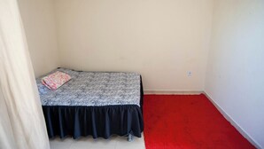 A small, single-bed room with a zebra-patterned bedspread and a red carpet. - Casa Pet Friendly com Varanda e Churrasqueira (Rio das Ostras)