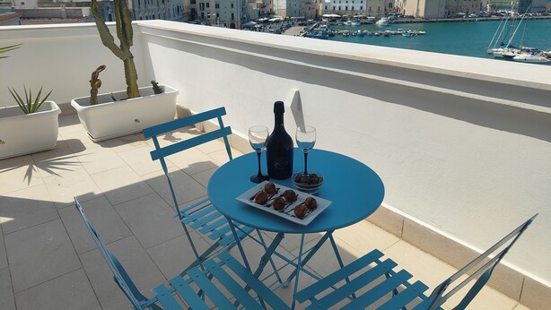 A terrace with a table set for two, featuring a bottle and glasses, and a plate of cookies. - SEA DREAM PALACE 1 (Trani)