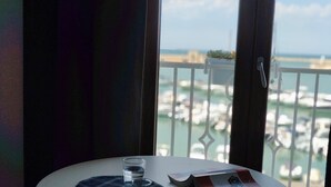A table with a placemat, a glass of water, and a menu on a balcony overlooking a marina. - SEA DREAM PALACE 1 (Trani)