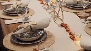 A long dining table set with plates, glasses, and candles, featuring a rustic wooden table and woven placemats. - Villa Victoria La Marsa (La marsa)