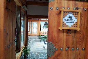 A wooden entrance with a sign, a stone pathway, and a view into a room with traditional decor. - Dajayon Hanok Stay (Seoul)