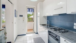 Eine Küche mit weißen Schränken, einem Gasherd und einer blauen gefliesten Spritzschutzwand.