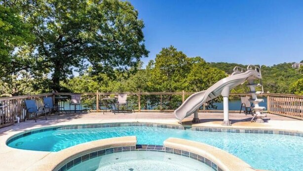 A swimming pool with a slide, surrounded by lounge chairs and a wooden deck. - Artilla Cove Resort # 3 (Branson)