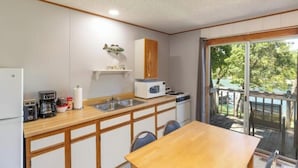 A compact kitchen with a wooden countertop, white cabinets, and a view of a deck through a glass door. - Artilla Cove Resort # 3 (Branson)