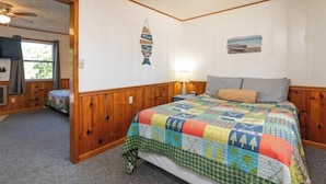 A bedroom with a wooden headboard, a colorful quilt, a small bedside table with a lamp, and a wall decoration. - Artilla Cove Resort # 3 (Branson)