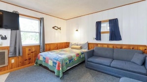 A cozy room with a bed, a sofa, a television, and a window with curtains. - Artilla Cove Resort # 3 (Branson)