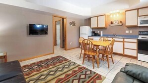 A compact kitchen with a dining area, a television, and a patterned rug.