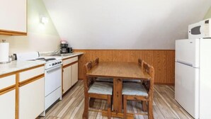 A kitchen with a wooden table, white cabinets, and a white refrigerator. - Artilla Cove Resort # 9 (Branson)